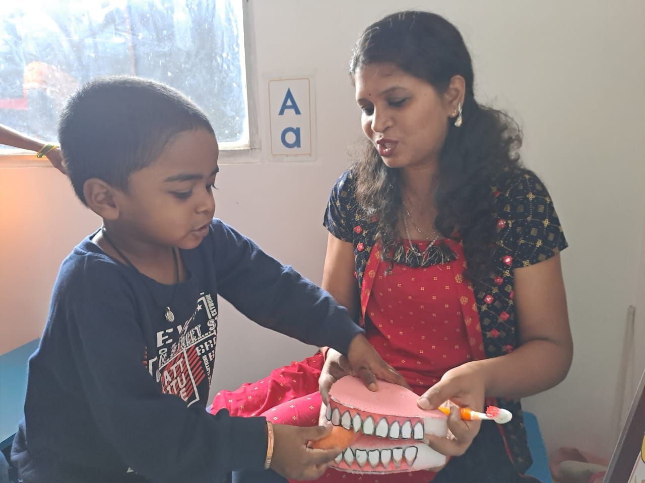 Teacher helping a child learn about healthy teeth